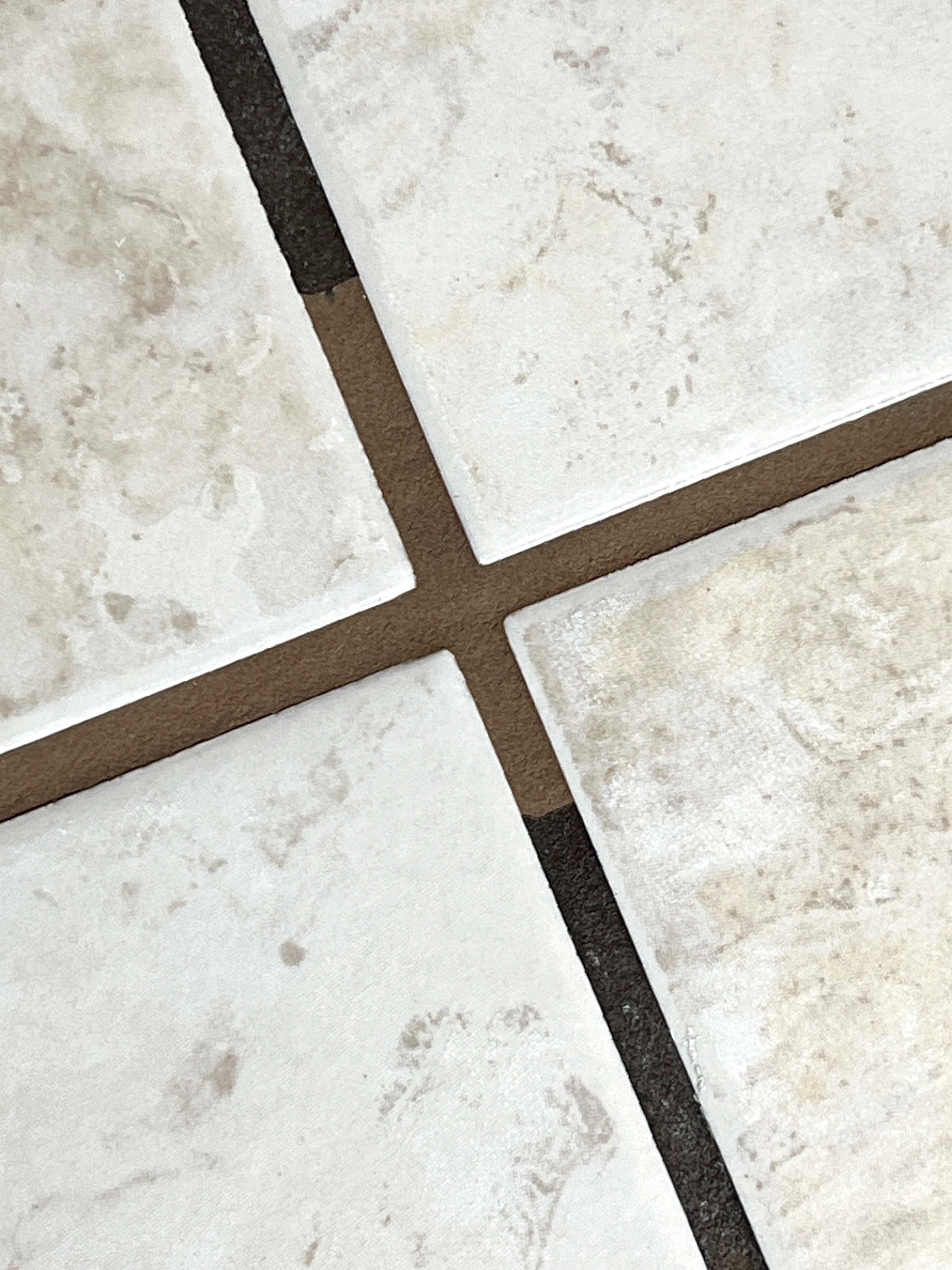 Close-up laser grout cleaning — spotless restored grout line beside black stained grout, Vancouver Island